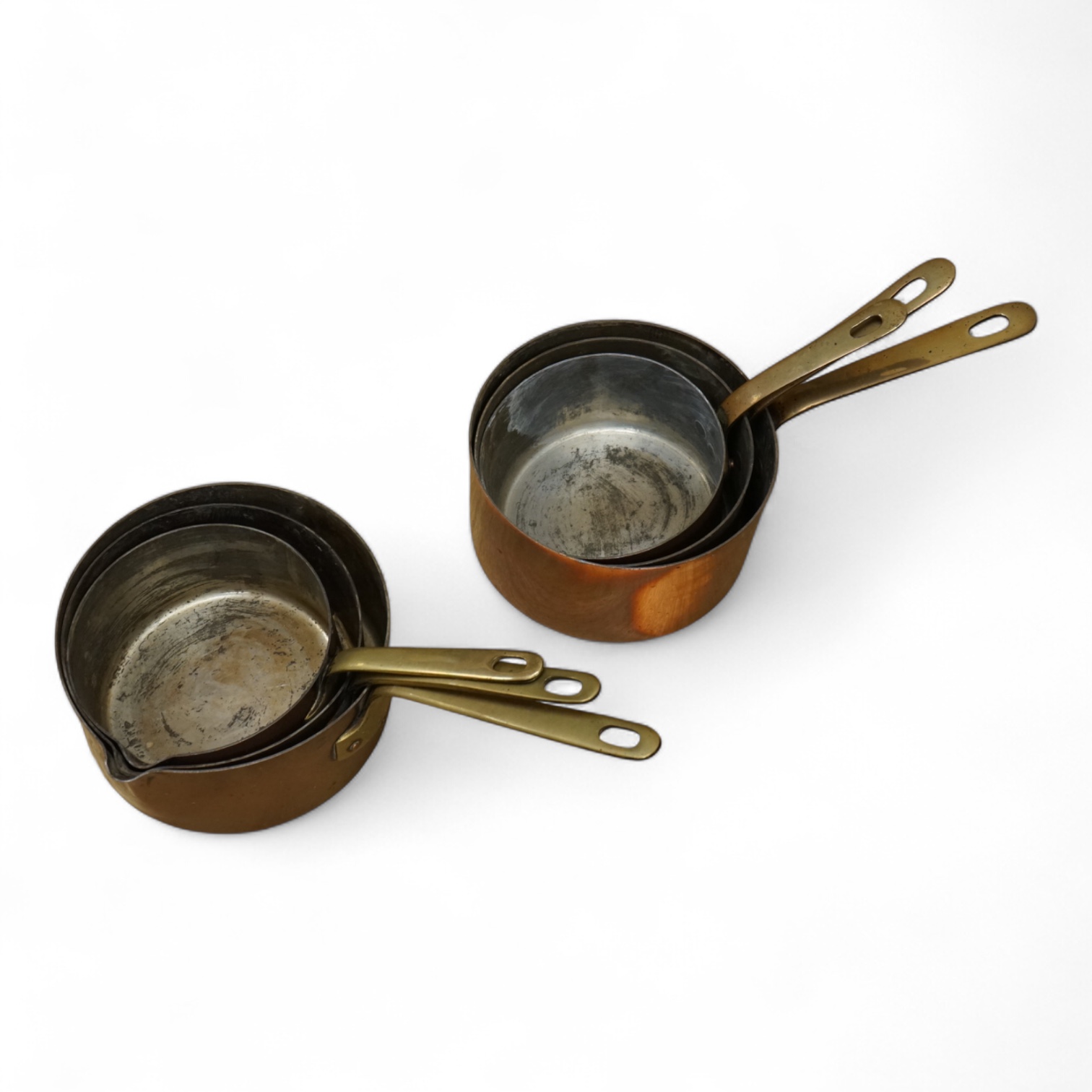 A set of three graduated copper and brass handled Saucepans and a similar set with pouring lid, largest 40cm in length